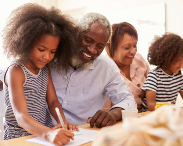 Grandparents Sitting At Table With Grandchildren Playing Games Together